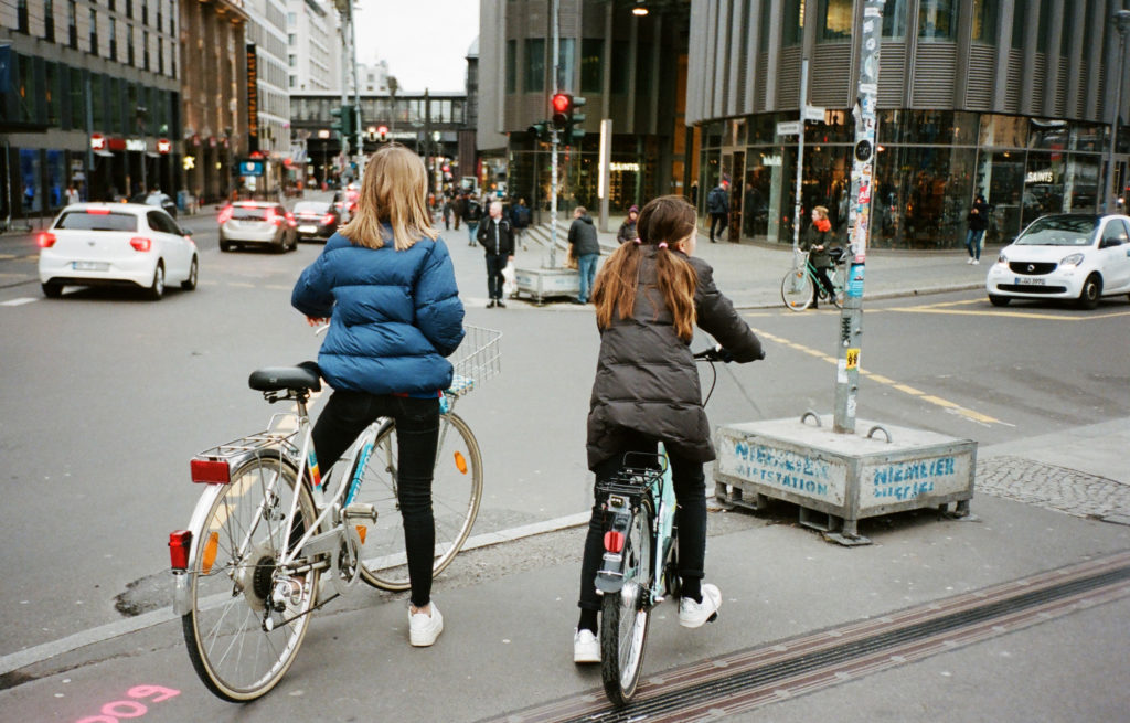 two women waiting on bikes to cross a road