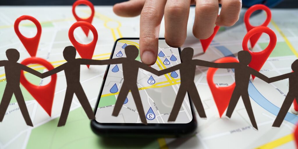 a line of paper people holding hands with GPS style geospatial map in background