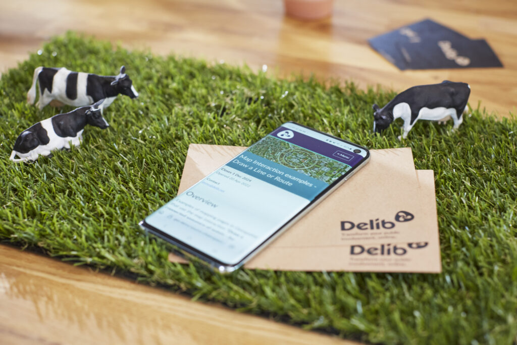 Delib geospatial shown on phone that's lying on top of a green mouse pad